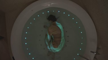 Jakuzideki kadın. Hisse. Jakuzideki en iyi giyinmiş genç kadın manzarası. Elbiseli kadın akşamları neon jakuzide yıkanıyor..