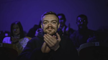 Genç adam tiyatro gösterisi izliyor. Medya. Adam tiyatro performansını yerinde seyrediyor. Seyirci, tiyatro performansındaki spot ışıklarıyla aydınlatıldı.