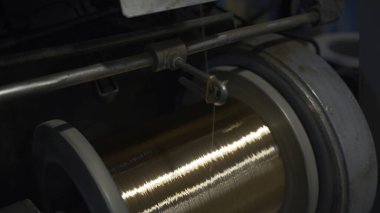 Sarmalı sarmalayan bakır kabloya yakın çekim. Yaratıcı. Parlak bakır tel, metalurji fabrikasındaki bobine sarılmış. Bakır kablo üretimi.