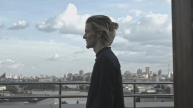 Genç adam binanın çatısında. Hisse. Genç adam binanın çatısındayken garip davranıyor. Yazın yüksek binaların terasındaki adam.. 