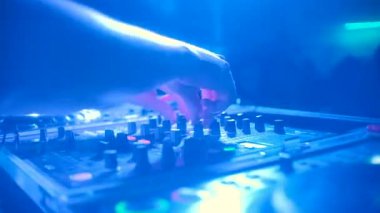 Kadın müzik mikserinin arkasında çalışıyor. Şarjör. Kulüpte DJ 'lik yapan genç bir kadın. Havalı bayan DJ gece diskosunda müzik açar..