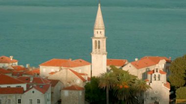 Kilise ve deniz dalgaları arka planında kulesi olan eski bir kasabanın zamanaşımı etkisi. Yaratıcı. Güzel doğa ve mimari