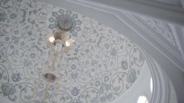 Modaya uygun bir bina manzarası. Geniş beyaz duvarlar ve mermerden yapılmış yüksek tavanlar ve duvarlara küçük sarı lambalar asmak. Yüksek kaliteli FullHD görüntüler
