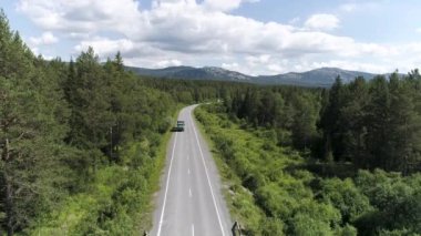 Ormandaki otobanda geçen arabanın en üst görüntüsü. Sahne. Güneşli bir günde ormanın olduğu güzel bir kır yolu manzarası. Şehir dışına seyahat..