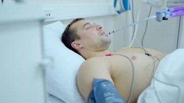 Kafkasyalı bir adam hastane odasında komadan çıkıyor. Başla. Hastane yatağında hasta bir adam, ağzında tüp olan bir hasta.