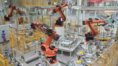 Rusya, Moskova - 7 Mayıs 2022: Robot ve işçilerle otomatikleştirilmiş fabrika. Sahne. Birçok robot makine modern fabrikada araba parçaları üretir. İşçilerin olduğu fabrikada modern robotik ekipman.