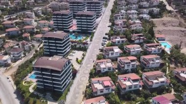Yüzme havuzlu villaların ve otellerin havadan görünüşü. Şarjör. Binaların ve yeşil ağaçların üzerinde uçuyor güneşin altında.