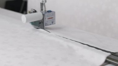 Tekstil ve giysi endüstrisinde yaygın olarak kullanılan otomatik kumaş kesme makinesinin yakın plan görüntüsü