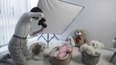 Samimi bir stüdyoda oyuncak hayvanlarla bebek fotoğrafı çeken profesyonel bir fotoğrafçı..