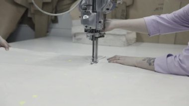 Tekstil üretim süreçlerini vurgulayan endüstriyel kumaş kesme makinesi kullanan bir işçi.