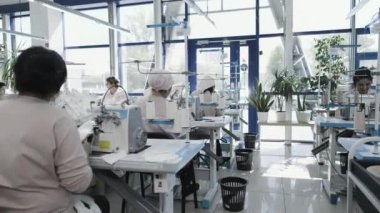 Modern bir tekstil fabrikasındaki işçiler dikiş makineleri işletiyorlar ve üretim, verimlilik ve takım çalışmasına odaklanıyorlar..