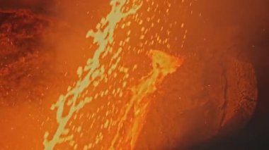 Fabrikada erimiş metal parçaları var. Stok görüntüleri. Erimiş metalin parlak damlaları akıntılarda hareket ediyor. Erimiş metal sıçramaları ve akıntıları olan metalik bitki..