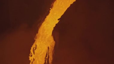 Erimiş metal akışı. Stok görüntüleri. Erimiş metal veya lav nehir yatağında hareket ediyor. Su sıçramış kırmızı-sıcak sıvı akımı. 