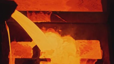Fabrikada parlak erimiş metal akıntıları. Stok görüntüleri. Erimiş metal akıntılar halinde kalıplara dökülür. Metal alaşımı metalürjik fabrikadaki kalıpları doldurur. 