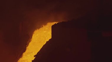 Erimiş metal akışı. Stok görüntüleri. Erimiş metal veya lav nehir yatağında hareket ediyor. Su sıçramış kırmızı-sıcak sıvı akımı. 