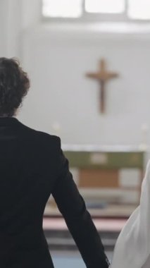 Kilisede yeni evliler. Başla. Yeni evliler arasında koridorda yürüyen zarif bir çift. Güzel yeni evliler kilisede nikah töreninde..