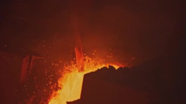 Erimiş metal akıntıları ve kanalları. Stok görüntüleri. İşçi, erimiş metalin metal bir rafla akmasını engelliyor. Erimiş alaşım yolunda katılaşmış metaller. 