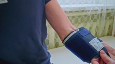 Hastanedeki basınç ölçümüne yakın çekim. Şarjör. Adam poliklinikte tansiyon ölçümü ile tıbbi muayeneden geçiyor. Hasta kolundaki basıncı ölçmek için bileklik.. 
