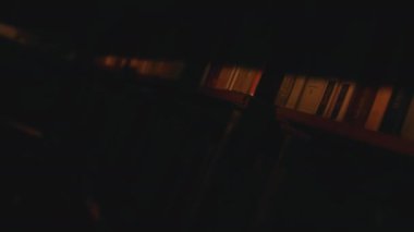 Kütüphanenin raflarındaki kitapları kapatıver. Stok görüntüleri. Kitaplarla dolu bir odada karanlık bir ışık