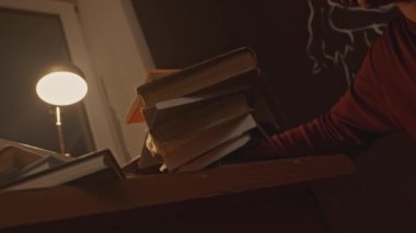 Uykulu bir öğrenci kitap yığınıyla masa başında uyuyakalıyor. Stok görüntüleri. İnsan sınava çalışmaktan yoruldu, hazırlık konsepti.