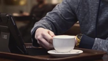 Kafeteryada elinde tepsiyle elinde bir fincan kahveyle bir erkek öğrenci. Stok görüntüleri. Kantinde sıcak içecek bulunan genç bir Kafkasyalı.