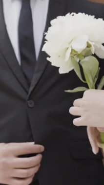 Düğün kostümleri. Eylem. Sokakta durup ellerinde beyaz bir çiçek tutan insanların güzel düğün kostümleri. Yüksek kalite 4k görüntü