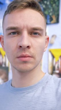 Sokak sanat galerisinin önünde selfie çeken bir adam. Başla. Tablolu mavi duvar, sanat ve yağlı boya resim konsepti