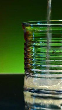 Masanın cam yüzeyindeki turunçgil kokteyli. Borsa klipsi. Meyveler ve biberiye yaprakları renkli ışıklandırılmış arka planda masanın üzerinde yatıyor.