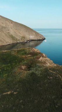 Dağın uzun yamacı. İnsansız hava aracının manzarası. Şut. Mavi, berrak deniz manzarası ve üzerinde küçük, beyaz binalar olan büyük dağlar. Yüksek kalite 4k görüntü