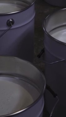 Bir kaç kova beyaz boya yakın. Medya. Endüstriyel arka plan, ev yenileme kavramı. Dikey video