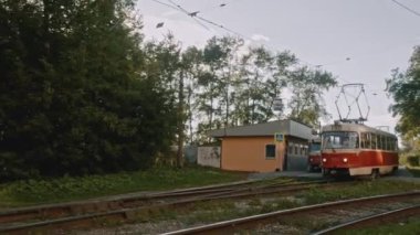 Yeşil ağaçların arka planında geriye doğru giden tramvay. Stok görüntüleri. Toplu taşıma kavramı