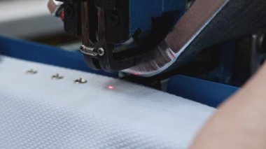 Dikiş fabrikasında otomatik yumruk makinesi. Medya. Düğmeler kopça düğmeli kumaş üzerine kuruluyor