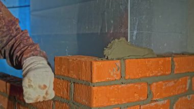 Evin içinde tuğla duvar döşeyen adamların yakın çekimi. Şarjör. Evin içine tuğla duvar örme işlemi. Duvarları döşenmiş tuğladan bir ev.. 