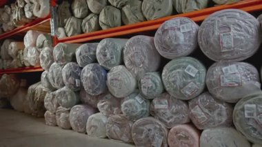 Tekstil fabrikası detayları, depo rafları. Medya. Tekstil ürünleri ve mallarla dolu büyük bir depo. Dikiş ya da mobilya üretimi