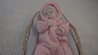 Bebek taşıyıcısının içinde sıcak pembe tulumlu küçük bebeğe yaklaş. Medya. Evdeki sevimli kız.