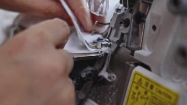 Dikiş makinesinin beyaz kumaştaki iğnesinin hızlı hareketi. Medya. Dikiş makinesinin iğnesi kumaşı dikiyor.