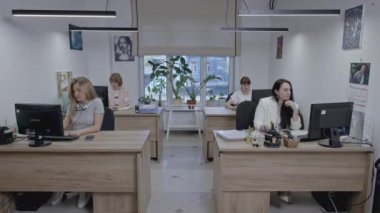 Kadınlar bilgisayar monitörlerine bakıyor, sandalyelerde oturuyor. Medya. Ofis çalışanları işlerini yapıyorlar.
