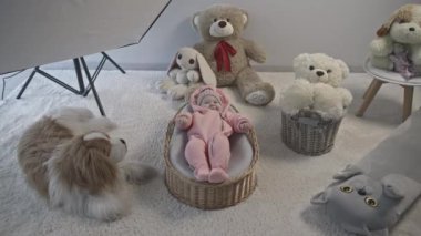 Pembe, sıcak takım elbiseli şirin bir bebeğin evde çekilmiş fotoğrafları. Medya. Stüdyonun içi oyuncaklarla dolu.