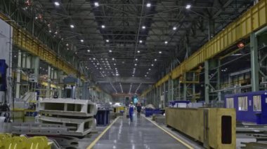 İşçilerle fabrika zemininin manzarası. Borsa klipsi. İşçilerle birlikte endüstriyel marangozluk atölyesi. Yürüyen işçiler ve makinelerle dolu büyük bir atölye koridoru.