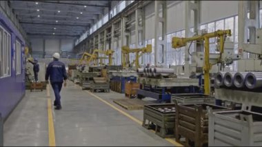 Fabrikada miğferi ve metal işçiliği olan bir işçi. Borsa klipsi. Fabrika makinesinde çalışma uzmanlığı. Modern otomatikleştirilmiş fabrika işçisi. 