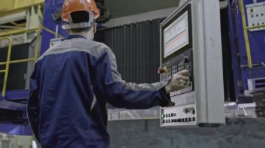 Fabrikada otomatik öğütme yapan bir işçi. Borsa klipsi. Otomatik makinenin uzaktan kumandalı işçisi. Somut dairesel yapı otomatik işlemle makinede döner. 