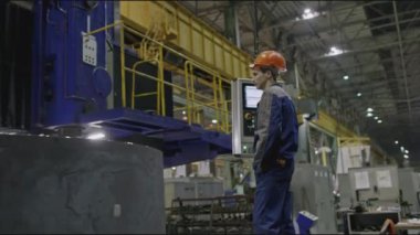 Fabrikada otomatik öğütme yapan bir işçi. Borsa klipsi. Otomatik makinenin uzaktan kumandalı işçisi. Somut dairesel yapı otomatik işlemle makinede döner. 