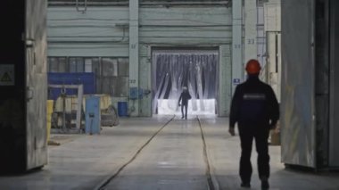 İşçiler endüstriyel depoda yürürler. Borsa klipsi. Sert şapkalı işçiler fabrikaya giderler. İşçiler sanayi bölgesinde yürüyor. 