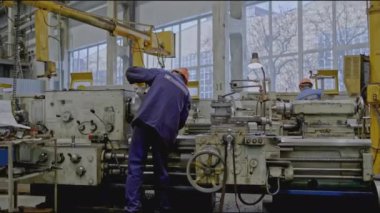 Makine aletleri olan fabrika işçileri. Borsa klipsi. Otomatik makinelerle metalürji fabrikasında vardiya. Makinelerin arkasında işçiler olan fabrika.. 