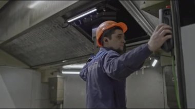 Fabrika ekipmanları için uzaktan kumandalı bir işçi. Borsa klipsi. İşçi ekipmanları kontrol etmek için uzaktan kumandayla kontrol ediyor. Makineleri çalıştırmak için uzmanlaşmış işçiler. 