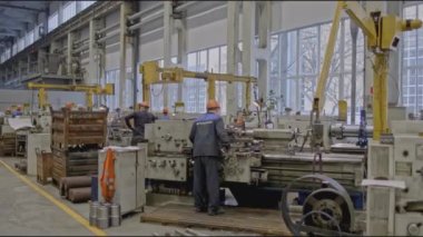Makine aletleri olan fabrika işçileri. Borsa klipsi. Otomatik makinelerle metalürji fabrikasında vardiya. Makinelerin arkasında işçiler olan fabrika.. 