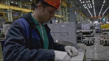 Fabrikadaki işçiler yapının ölçümlerini yapıyorlar. Borsa klipsi. Sert şapkalı işçiler yapının parçalarını bant ile ölçerler. İşçi sipariş için fabrika tasarımının bir kısmının ölçümlerini yapıyor. 