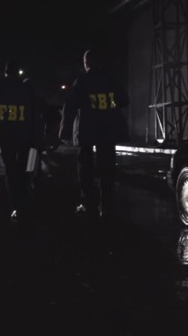 FBI ajanları olay yerinde, dikiz aynasından. Sahne. Federal Soruşturma Bürosu ajanları ağır çekimde yürüyorlar..