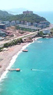 Turkuaz deniz ve kum kıyısının havadan görünüşü. Şarjör. Yaz tatili ve turizm kavramı, güney kasaba ve yeşil tepeler