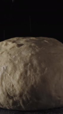 Yağmurlama un hamur, siyah arka plan close-up. Çerçeve. Un hamur koyu arka plan üzerine serpin.